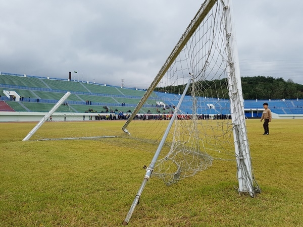 축구 골대가 부서져 있는 가운데 멀리 줄다리기 경기가 펼쳐지는 모습이 보인다.